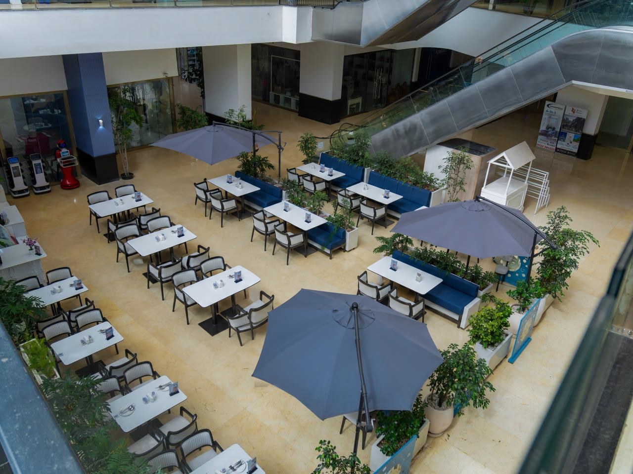 The Robot Cafe dining floor in the atrium at Lana Plaza, Kileleshwa, with blue banquettes, dining tables and potted plants
